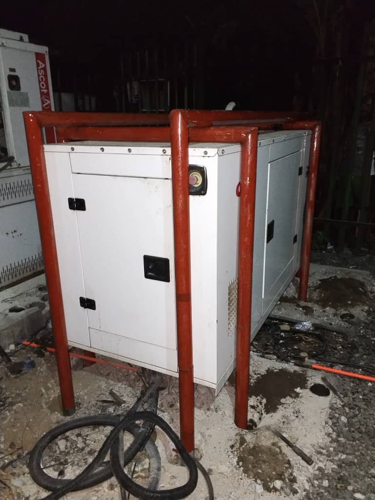 Sound-attenuated standby generator inside a red protective frame at a commercial site